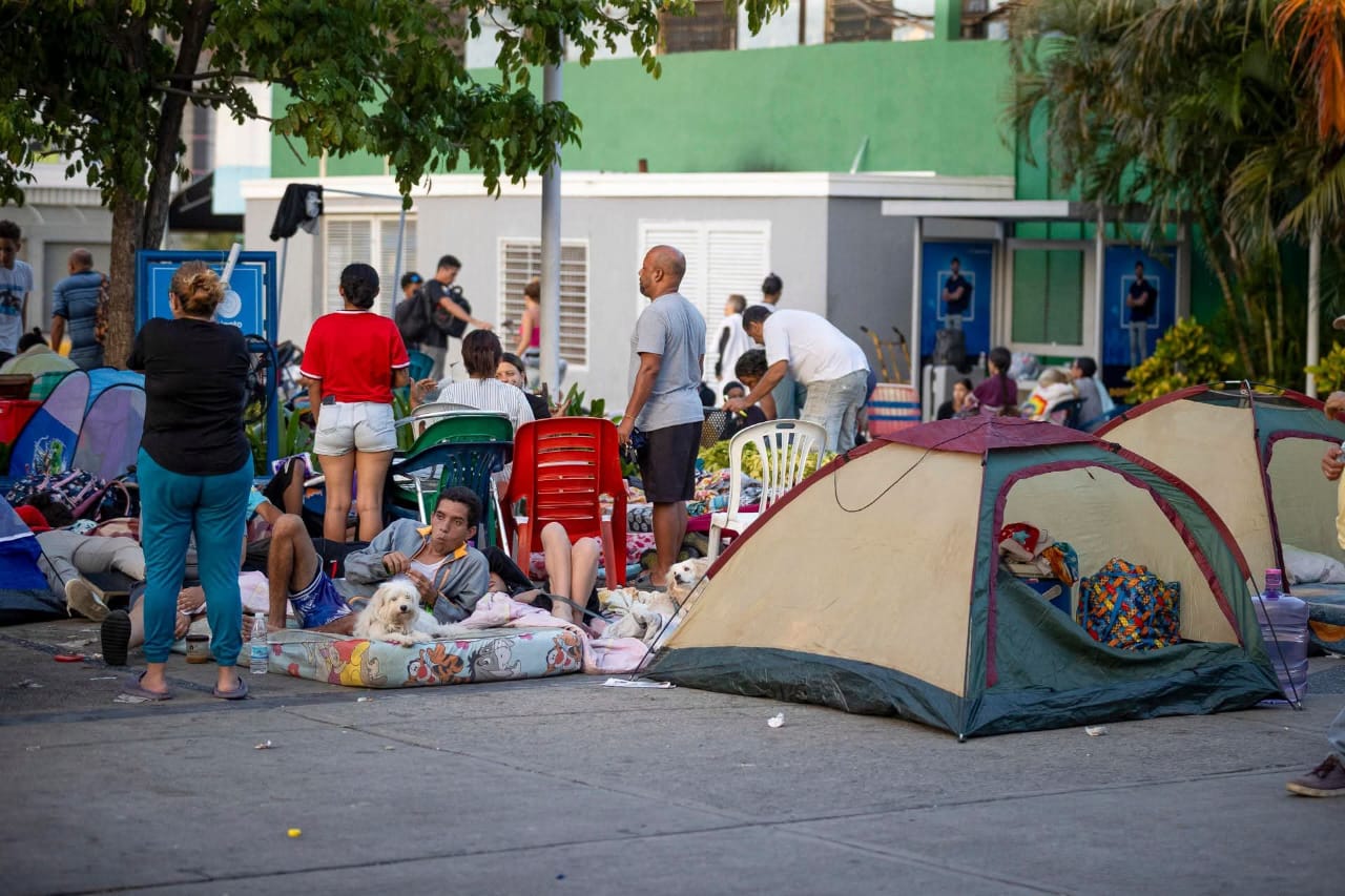 Familias damnificadas en una plaza con carpas, colchones en el piso y enseres improvisados